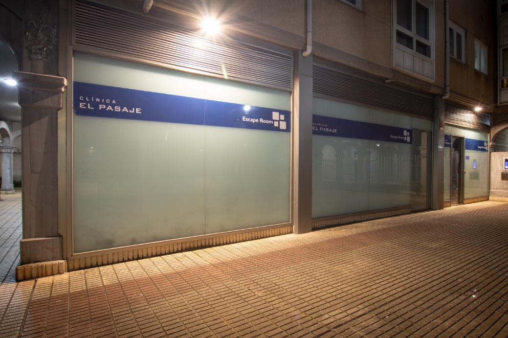 Fachada principal iluminada de noche de Clínica El Pasaje Escape Room en A Coruña, mostrando el cartel rojo luminoso y la entrada.